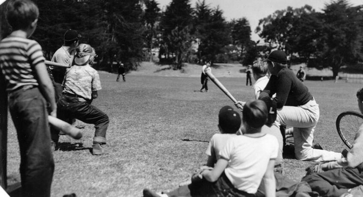 A group of boys watching an informal game of baseball