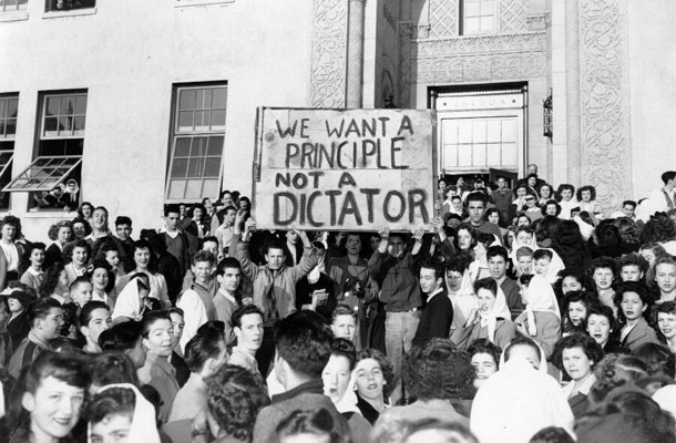 A group of students holding a sign that says 'We want a principle [sic] not a dictator'
