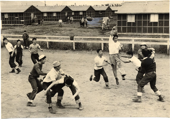 Japanese American teenage boys playing football in jeans and T-shirts